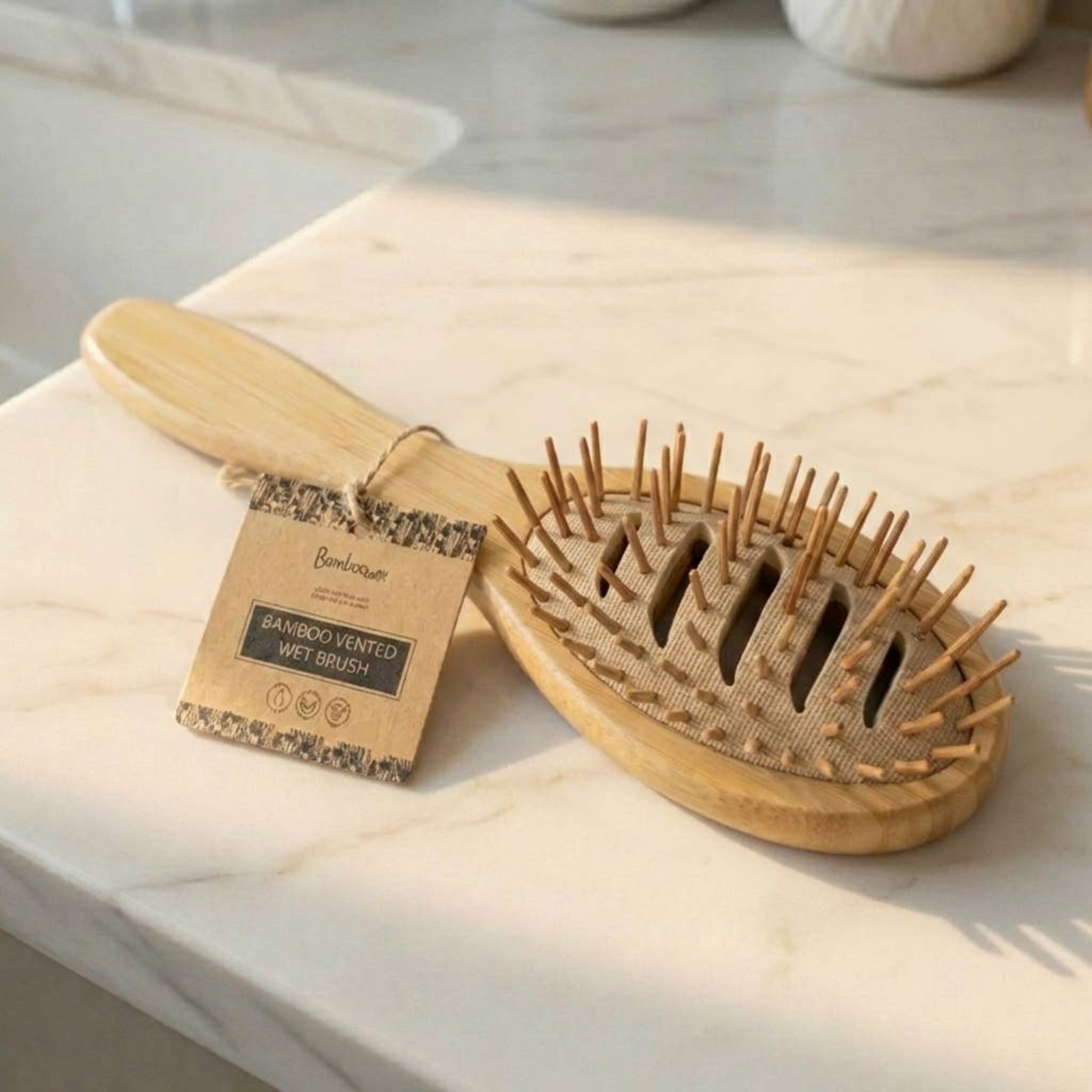 Bamboo vented wet hair brush with oval wooden pad, pin bristles, and product tag