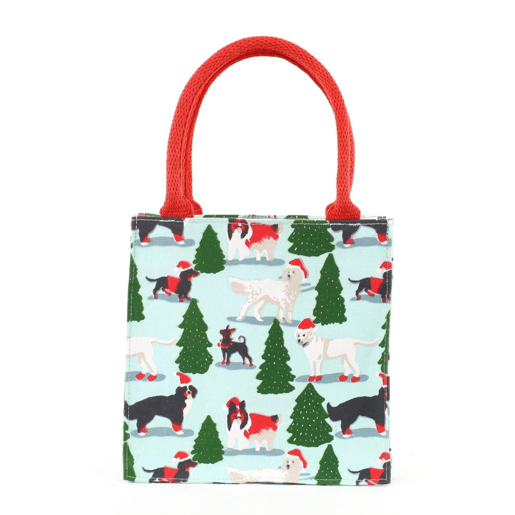 A small tote bag with a festive Christmas dog print on a light blue background, featuring red rope handles and a pattern of dogs wearing Santa hats and surrounded by green Christmas trees.