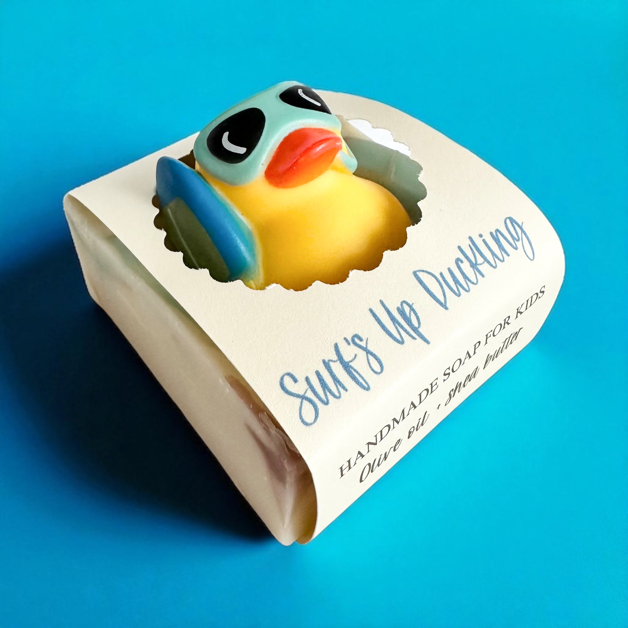 Kids handmade soap bar with blue-and-yellow duckling design on labeled packaging.