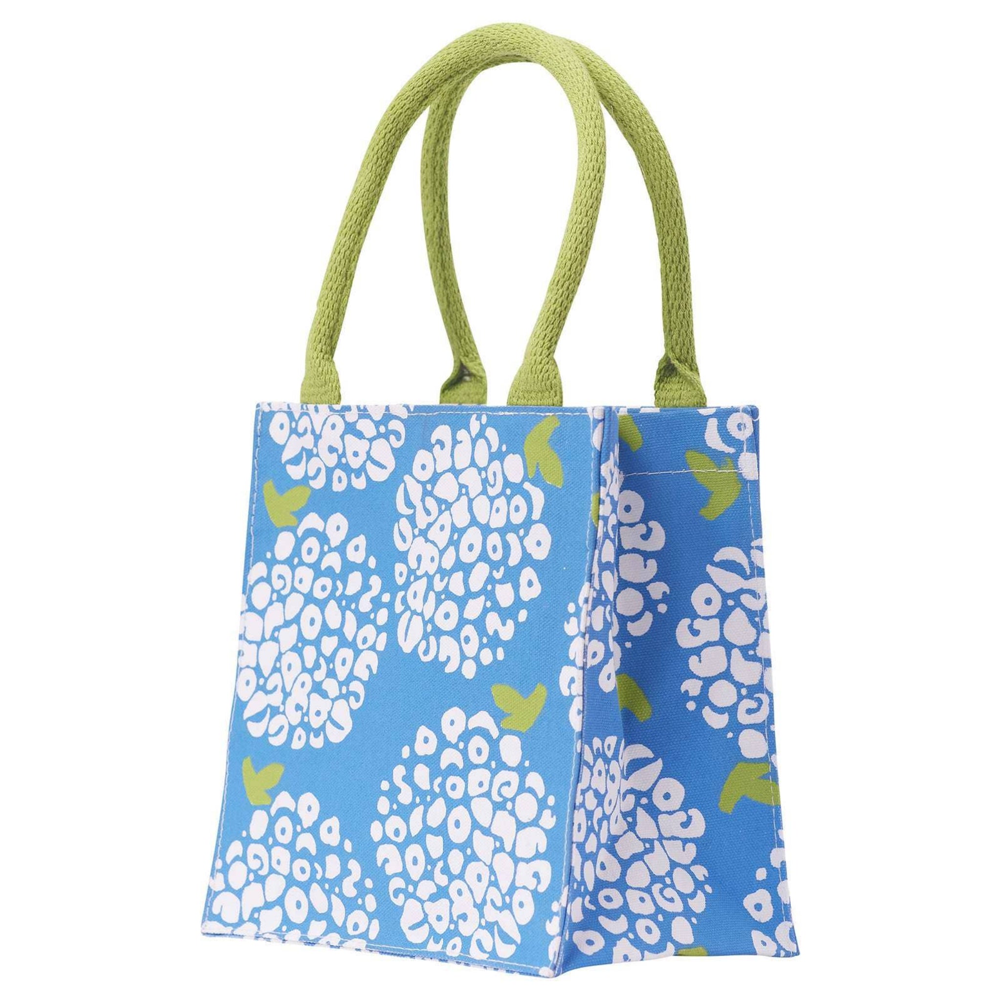 Blue tote bag with white floral pattern and green handles on a white background