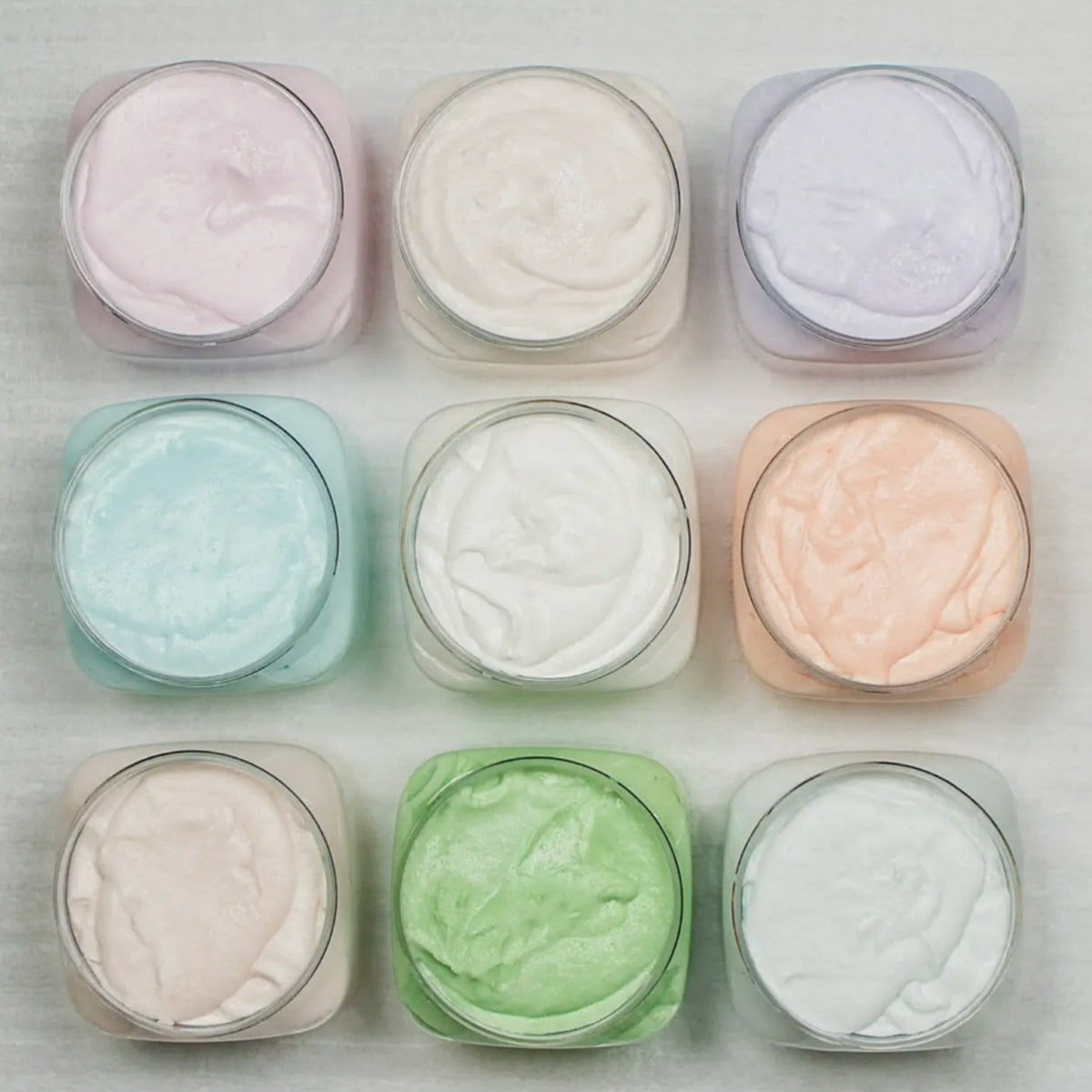 Six round exfoliating body polish & cleanser tins in pastel colors