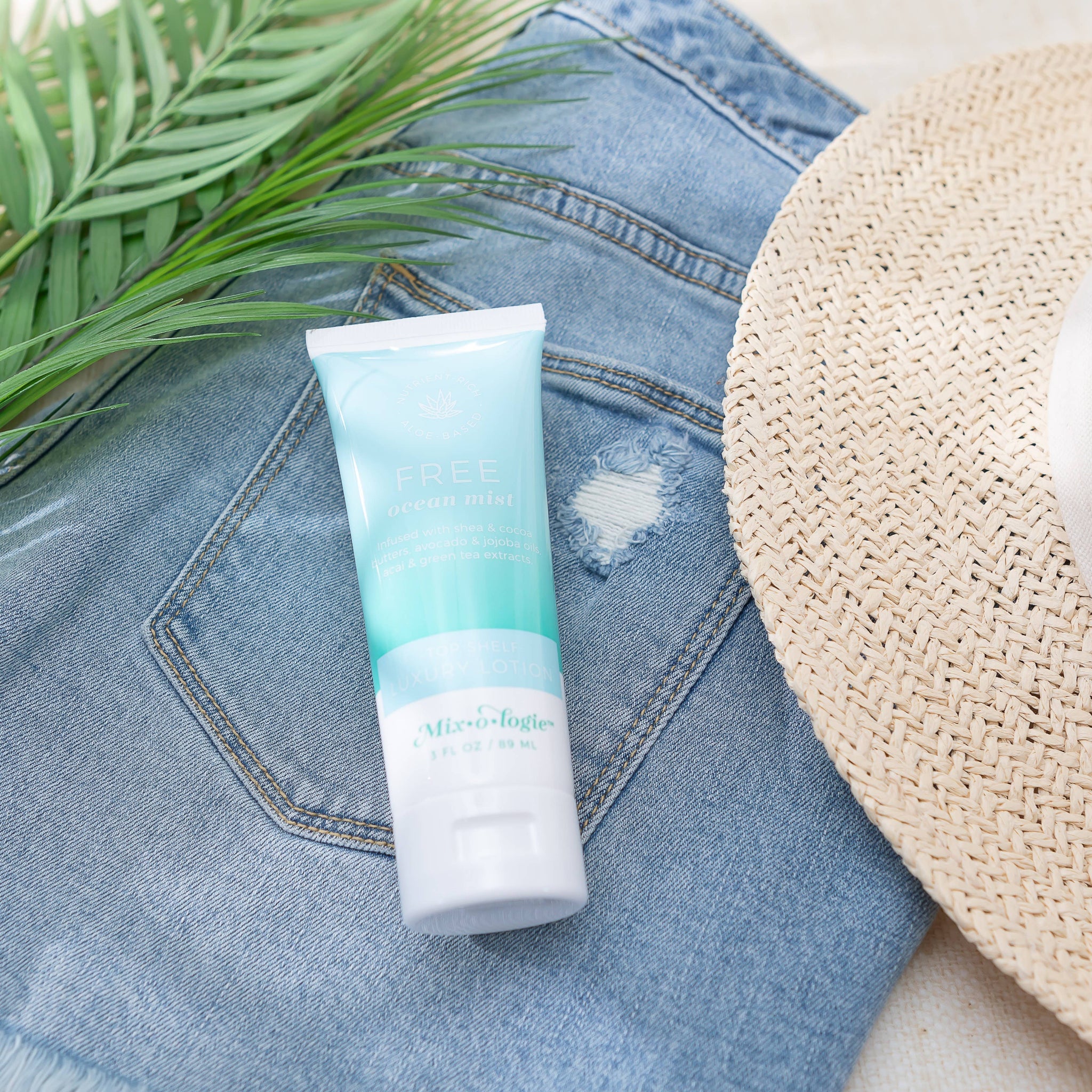 Tube of sunscreen on denim fabric with a hat and leaves in the background
