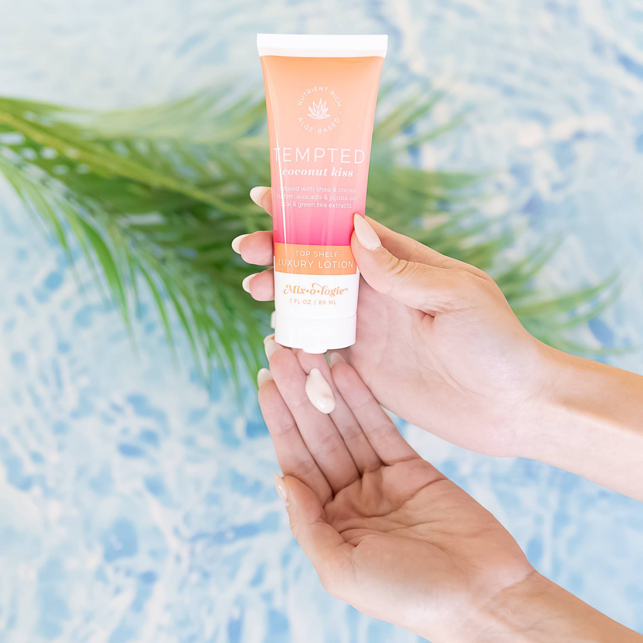 Hand holding a tube of sunscreen with a blurred natural background