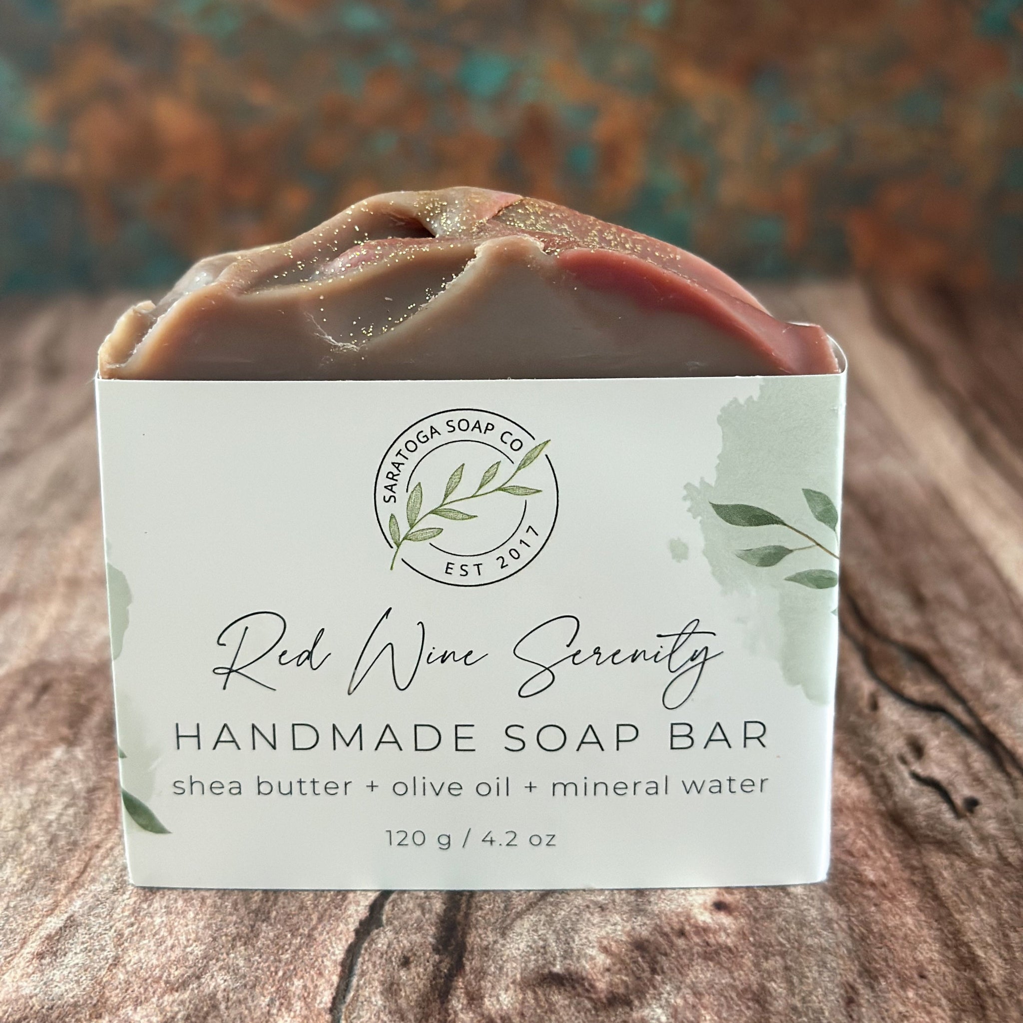 Dark red handmade soap bar in white logo box, close view