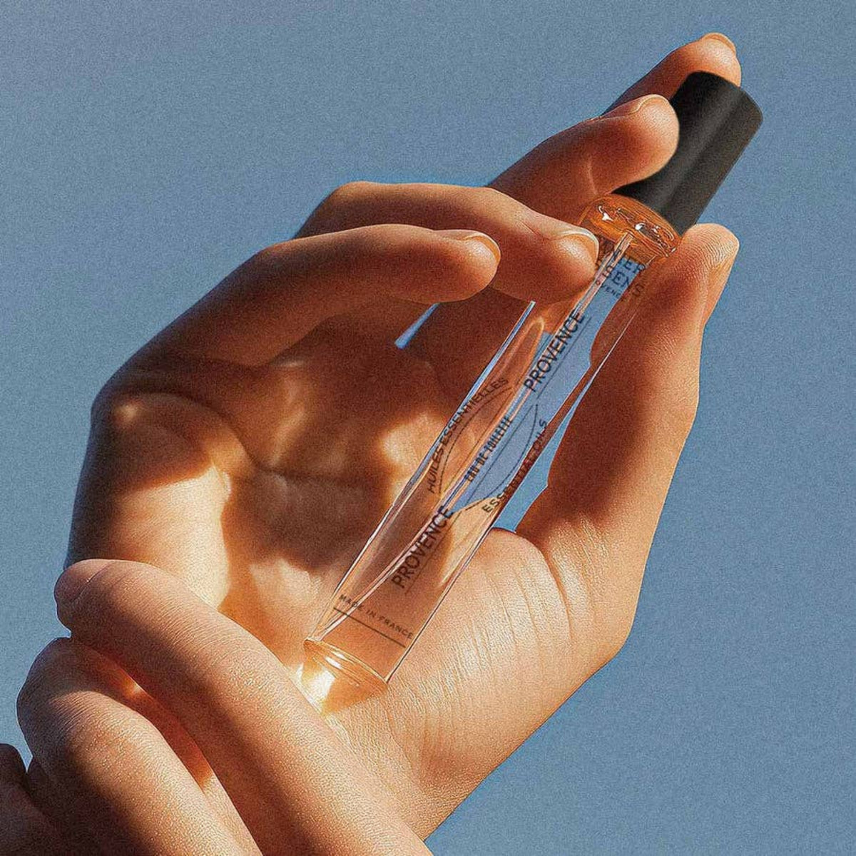 Hand holding a small rose fragrance bottle