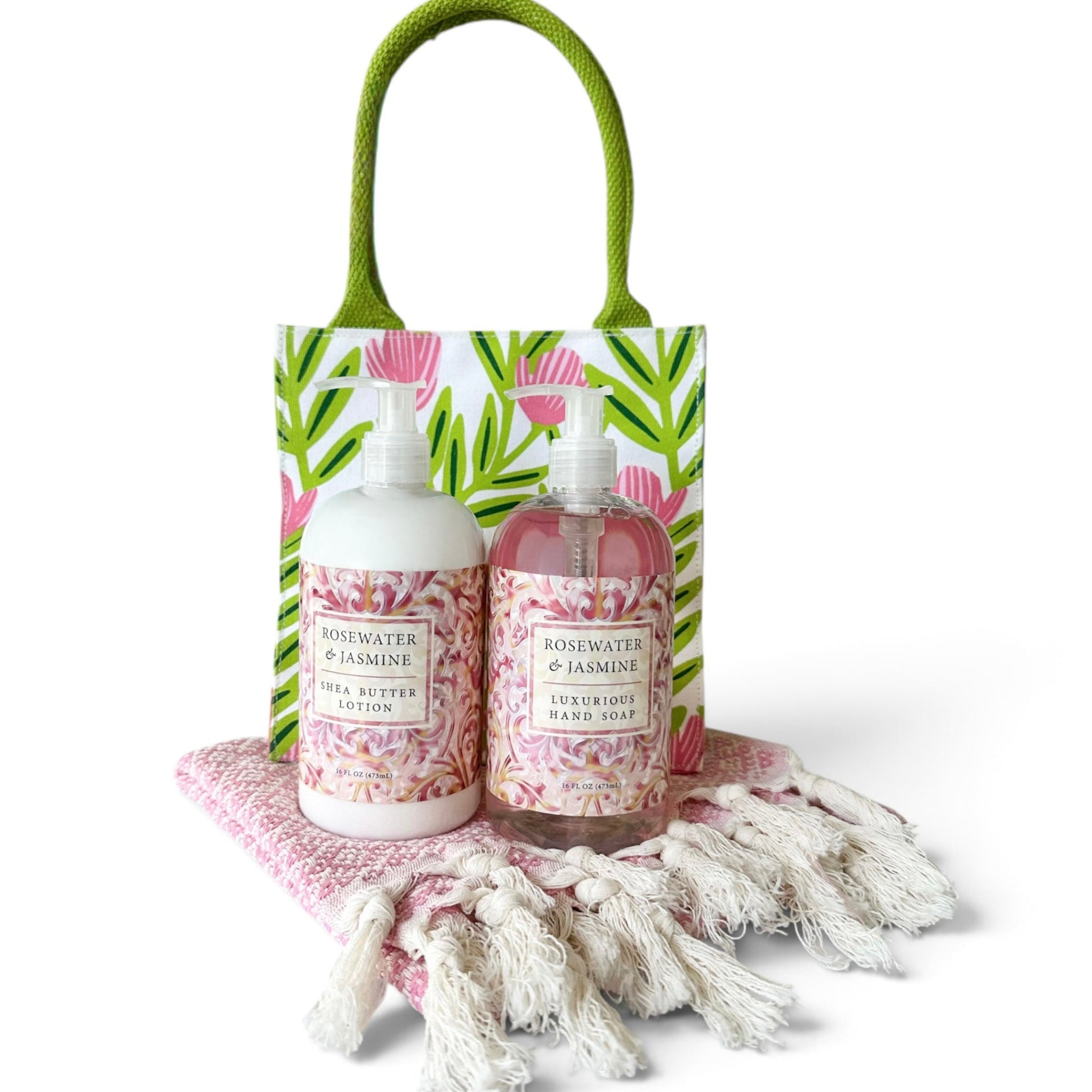 A gift set featuring two bottles of Rosewater & Jasmine body products, a green tote bag with a pink floral print, and a pink fringed throw blanket on a white background.