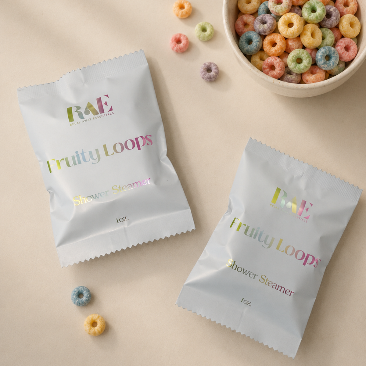 Two packets of 'Fruity Loops' shower steamers on a beige surface with colorful cereal loops.