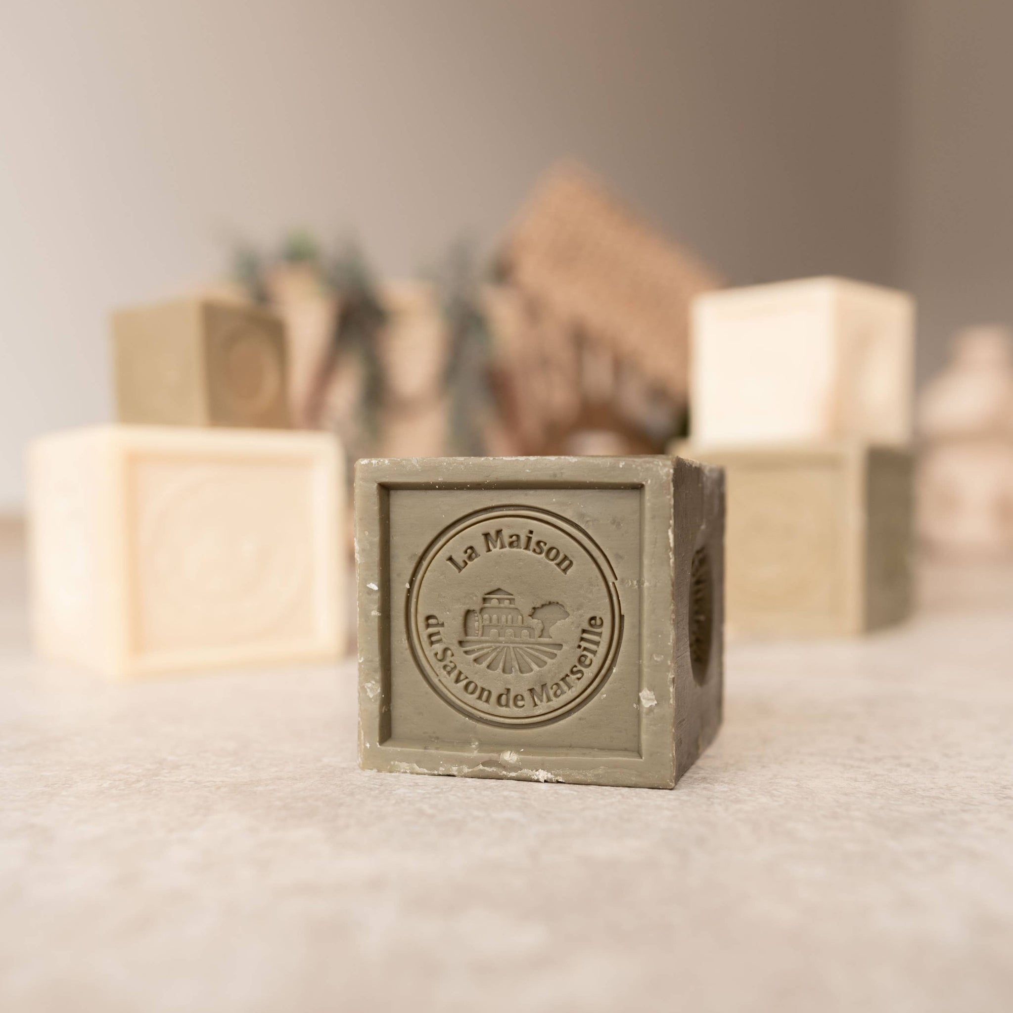 Marseille soap cube with round seal on a white dish beside other cubes