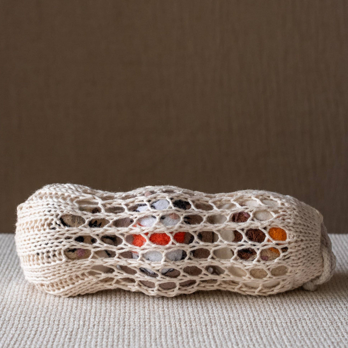 Natural wool dryer ball with crocheted cat face design, off-white with colorful accents