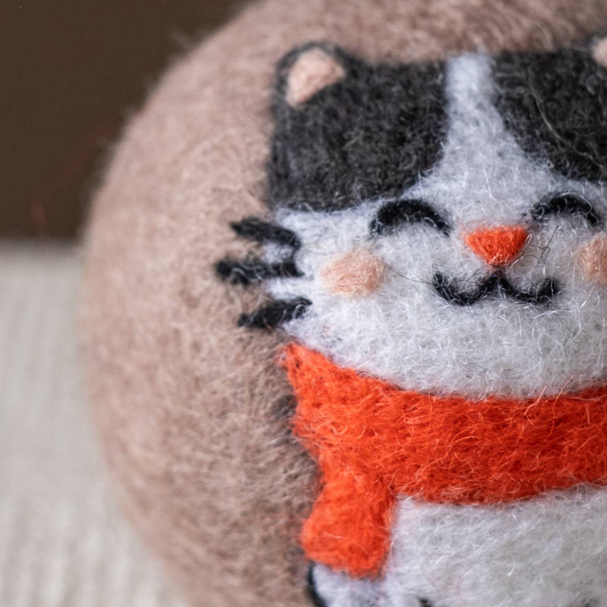 Natural wool dryer balls gift set of 3, close-up of a cat-face ball with orange scarf