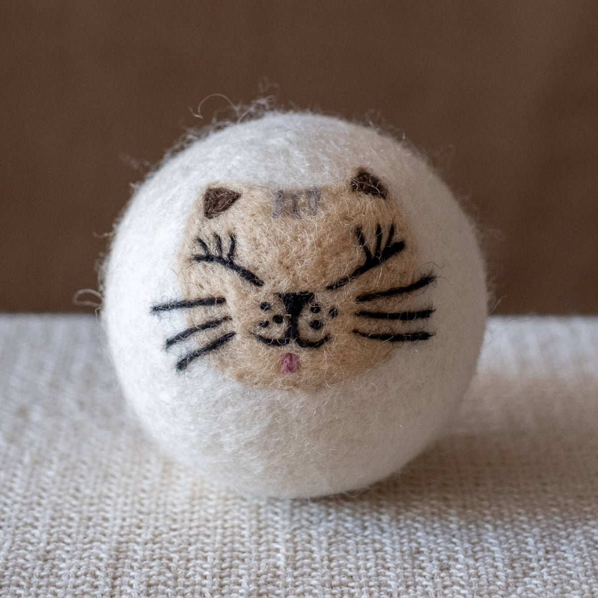 Natural wool dryer balls gift set of 3, light cat-face dryer ball on textured fabric