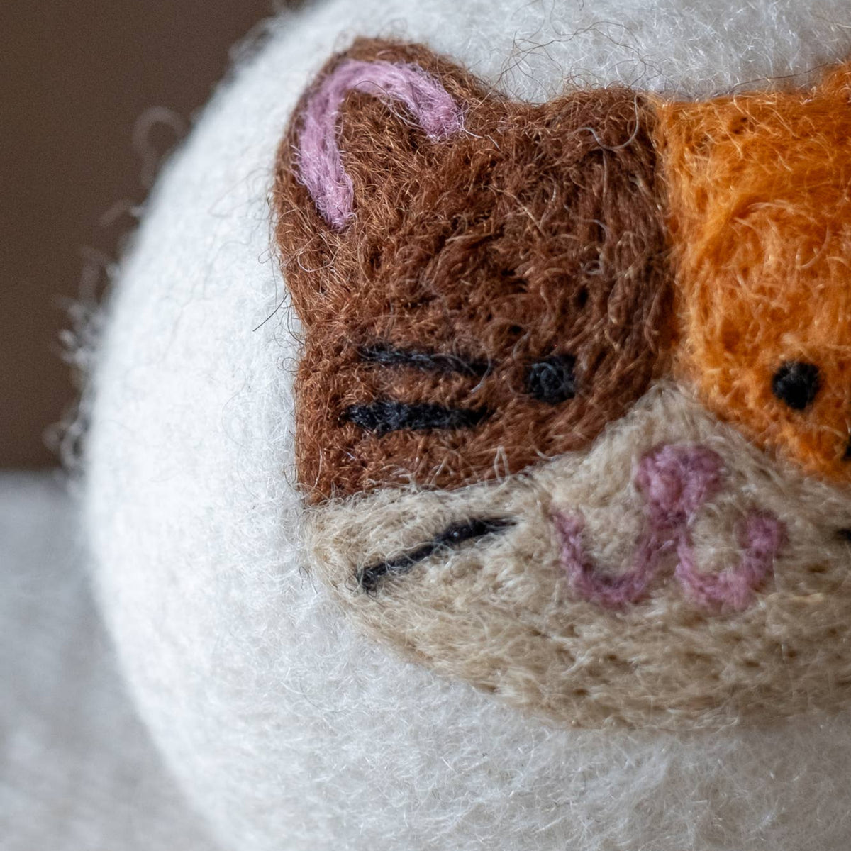 Natural wool dryer balls gift set of 3, close-up of a cat-face ball with brown and orange ears