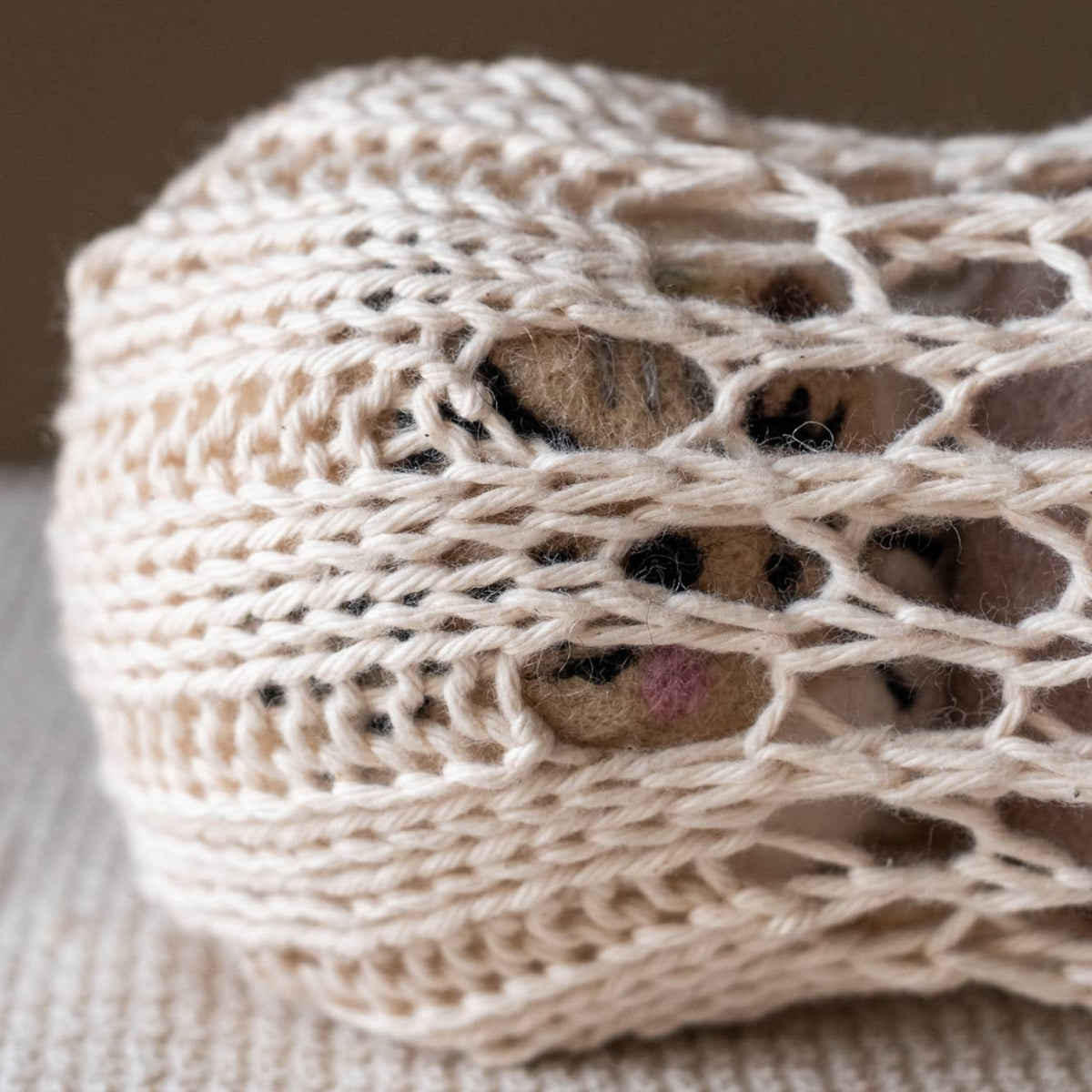 Natural wool dryer ball close-up with crocheted cat face, off-white and gray details