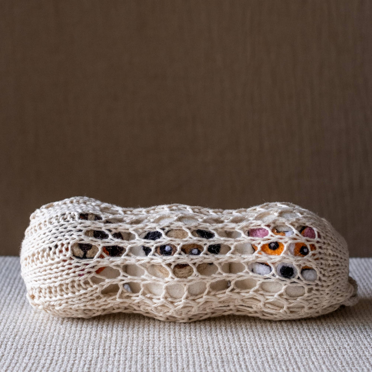 Natural wool dog-themed dryer ball with knit mesh and multicolor paw motifs