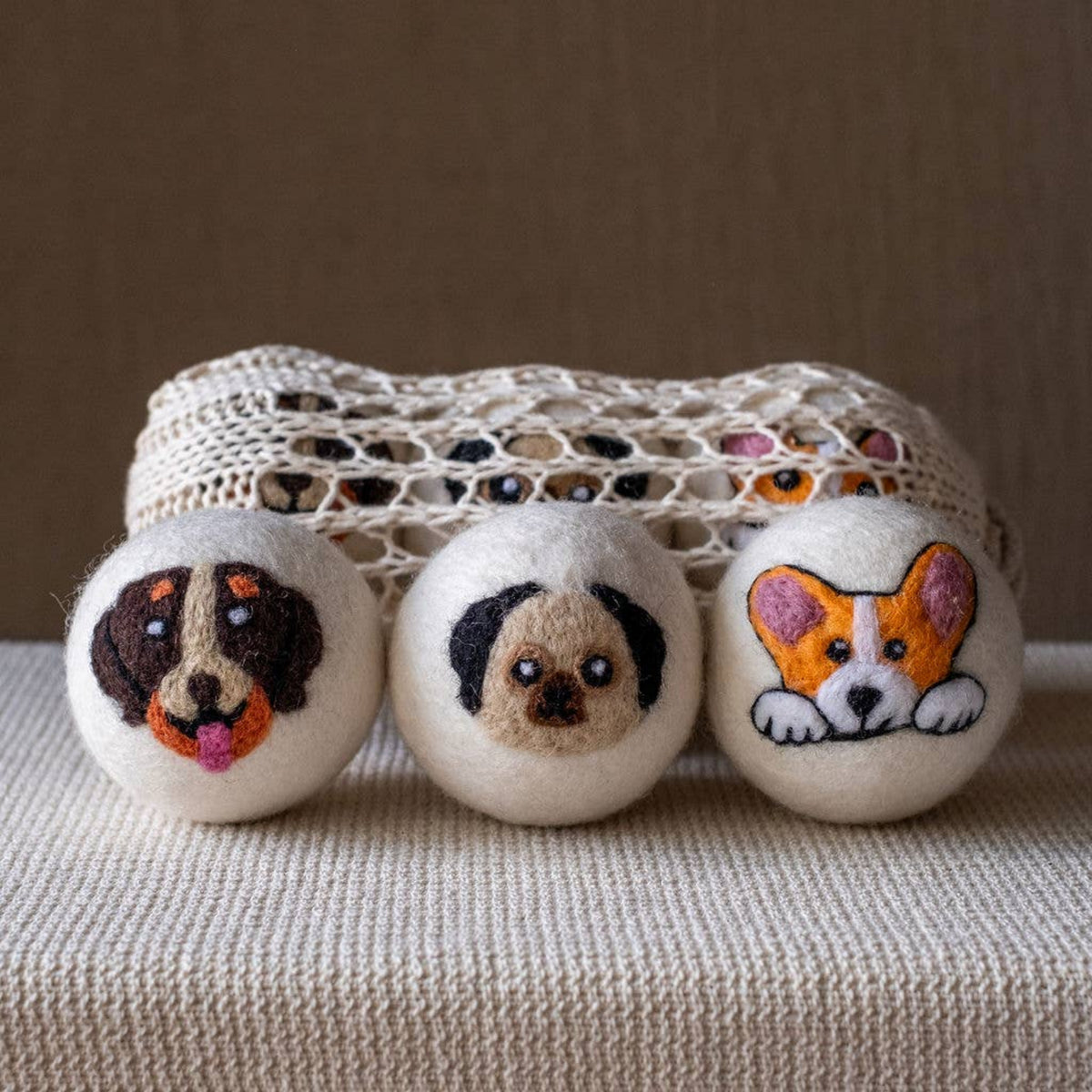 Set of three natural wool dryer balls with dog-face embroidery in light and dark tones