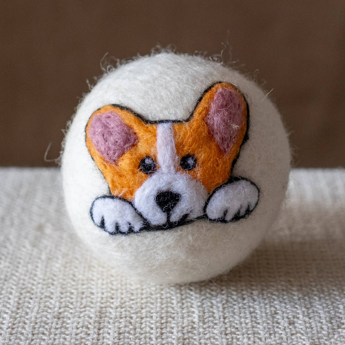 Natural wool dryer ball with stitched corgi face, orange and purple accents