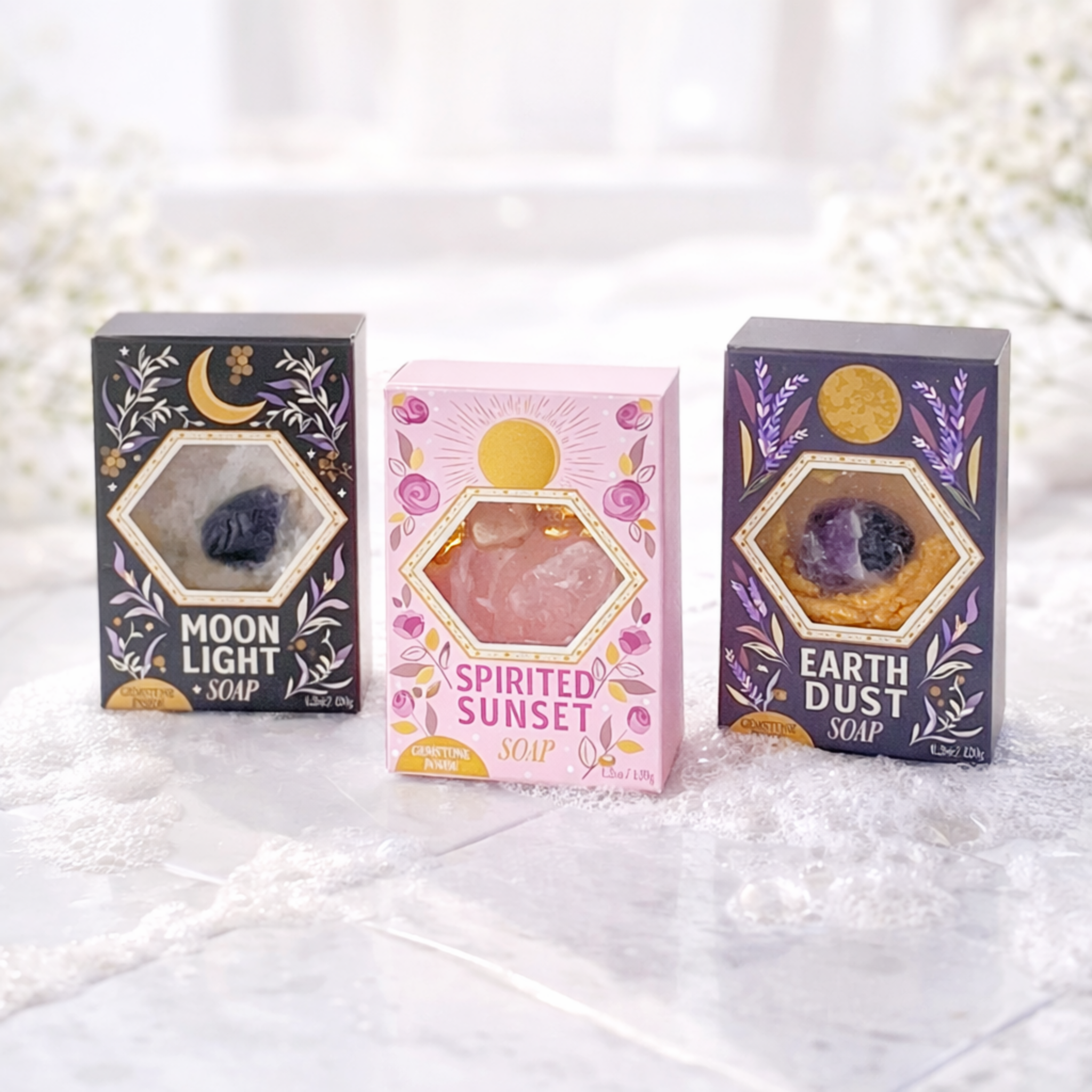 Three soap packages labeled 'Moon Light Soap', 'Spirited Sunset Soap', and 'Earth Dust Soap' on a textured white surface.