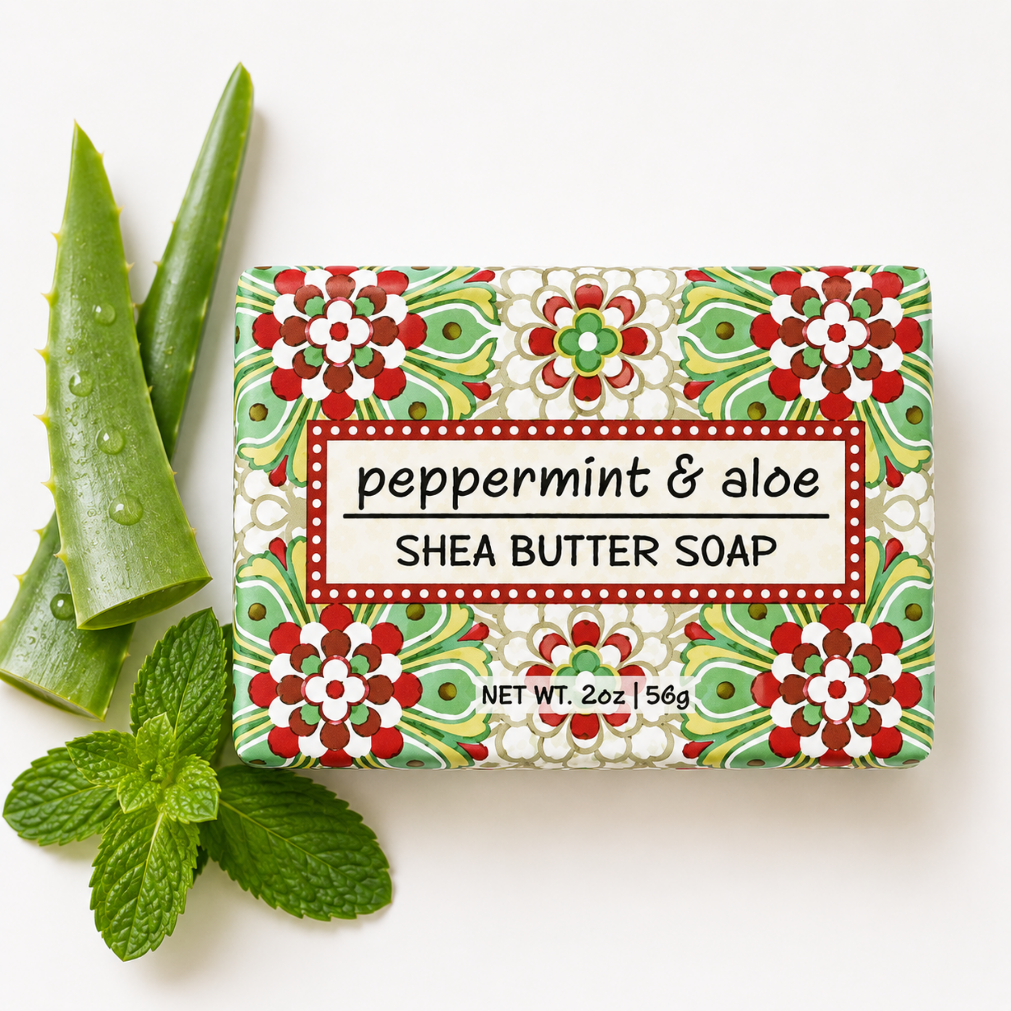 A rectangular bar of peppermint & aloe shea butter soap with a colorful floral patterned wrapper, styled with fresh aloe vera leaves and mint leaves on a white background.