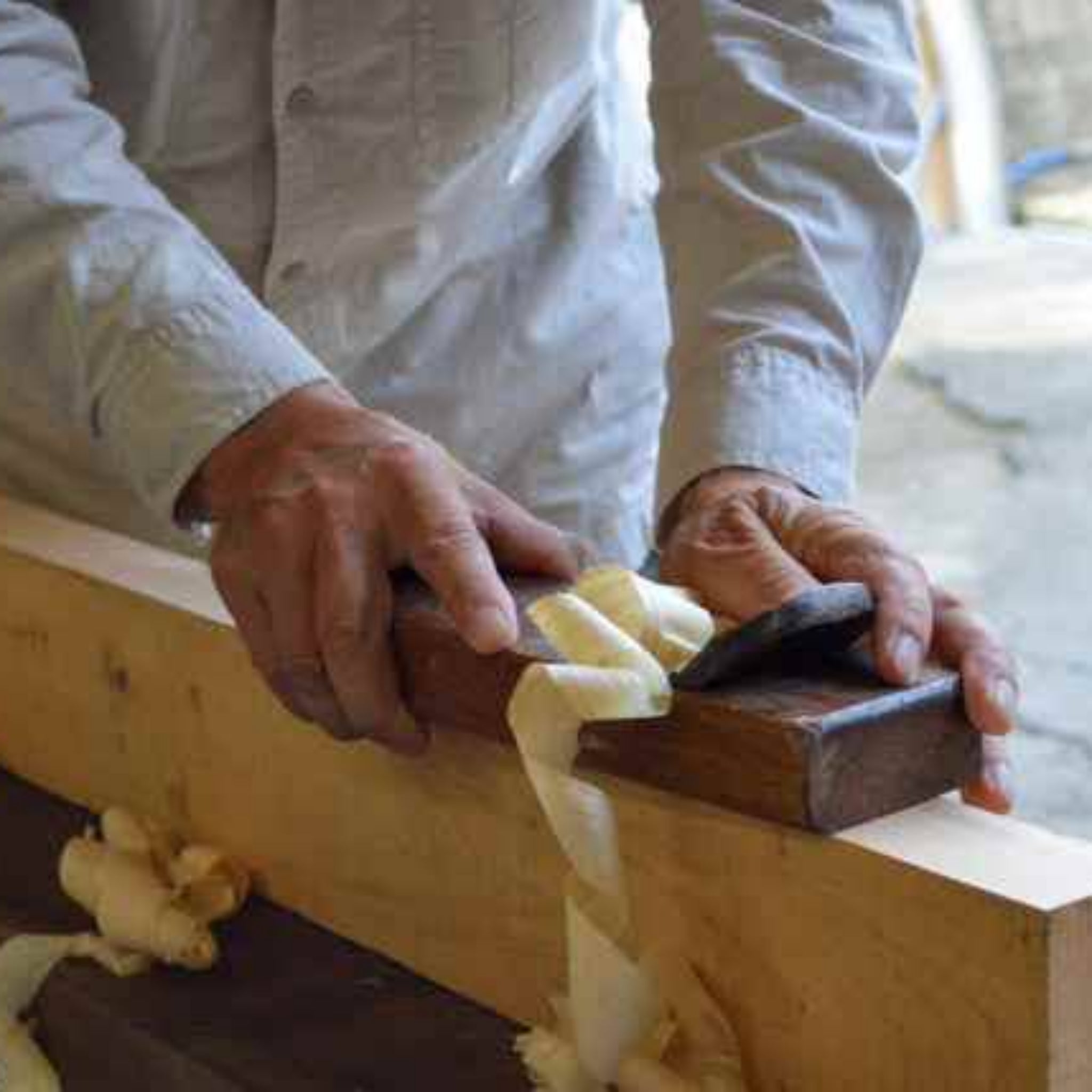 Person sanding a wooden board with sandpaper