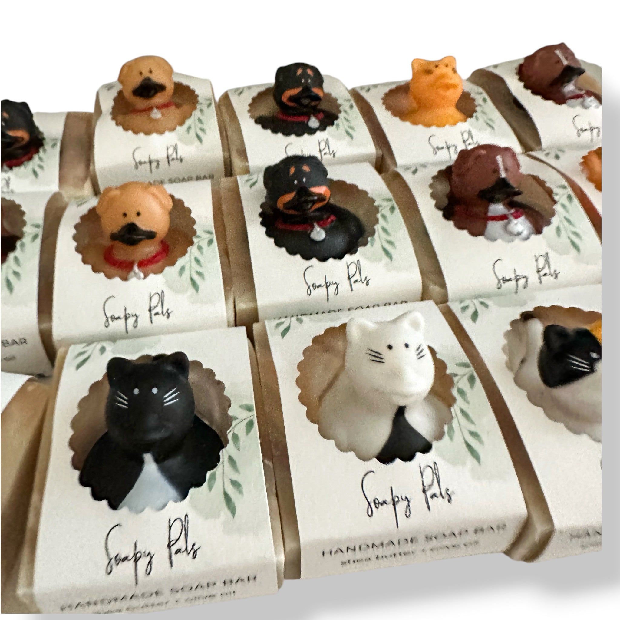 Assorted handmade soap bars shaped like cats and dogs in a wrapped tray.