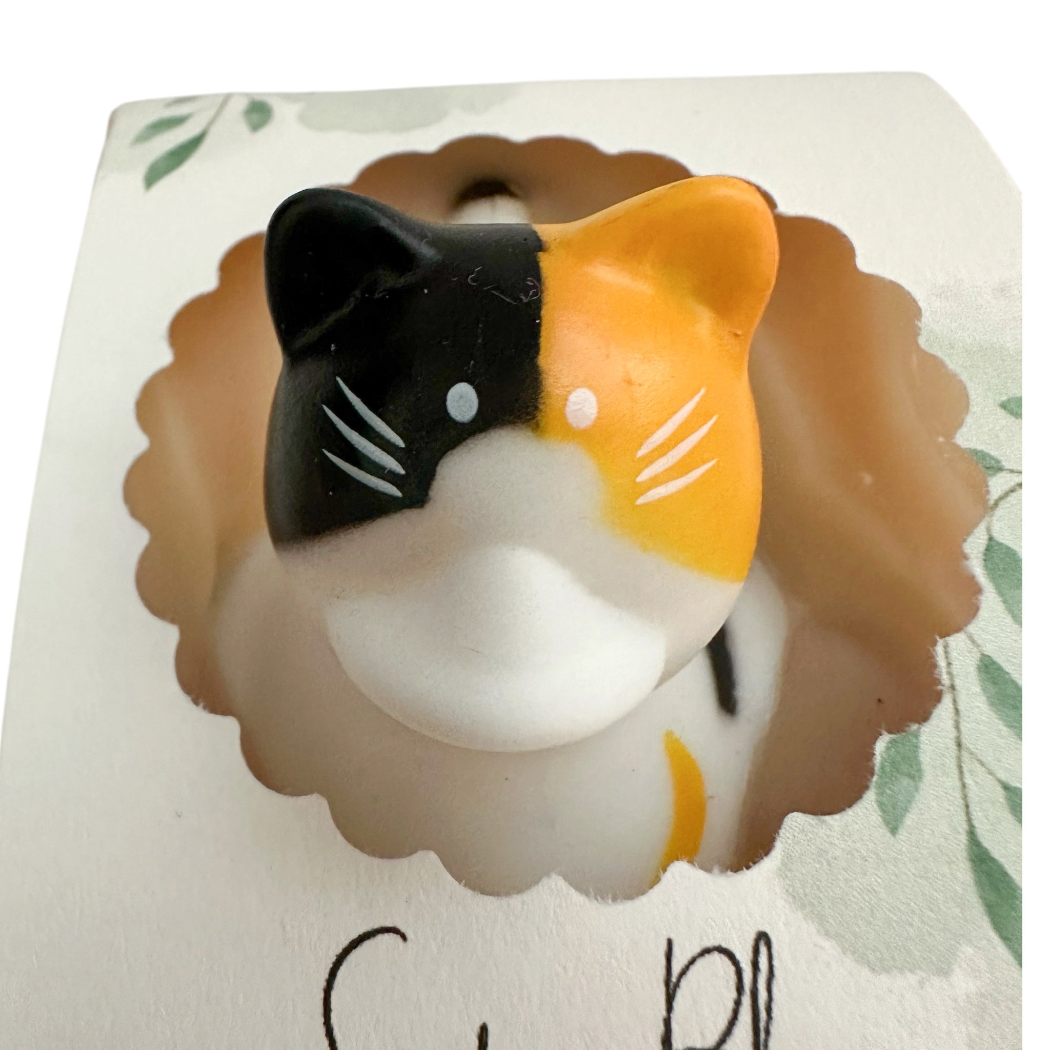 Handmade soap bar shaped like a black-and-orange cat with white muzzle and whiskers.