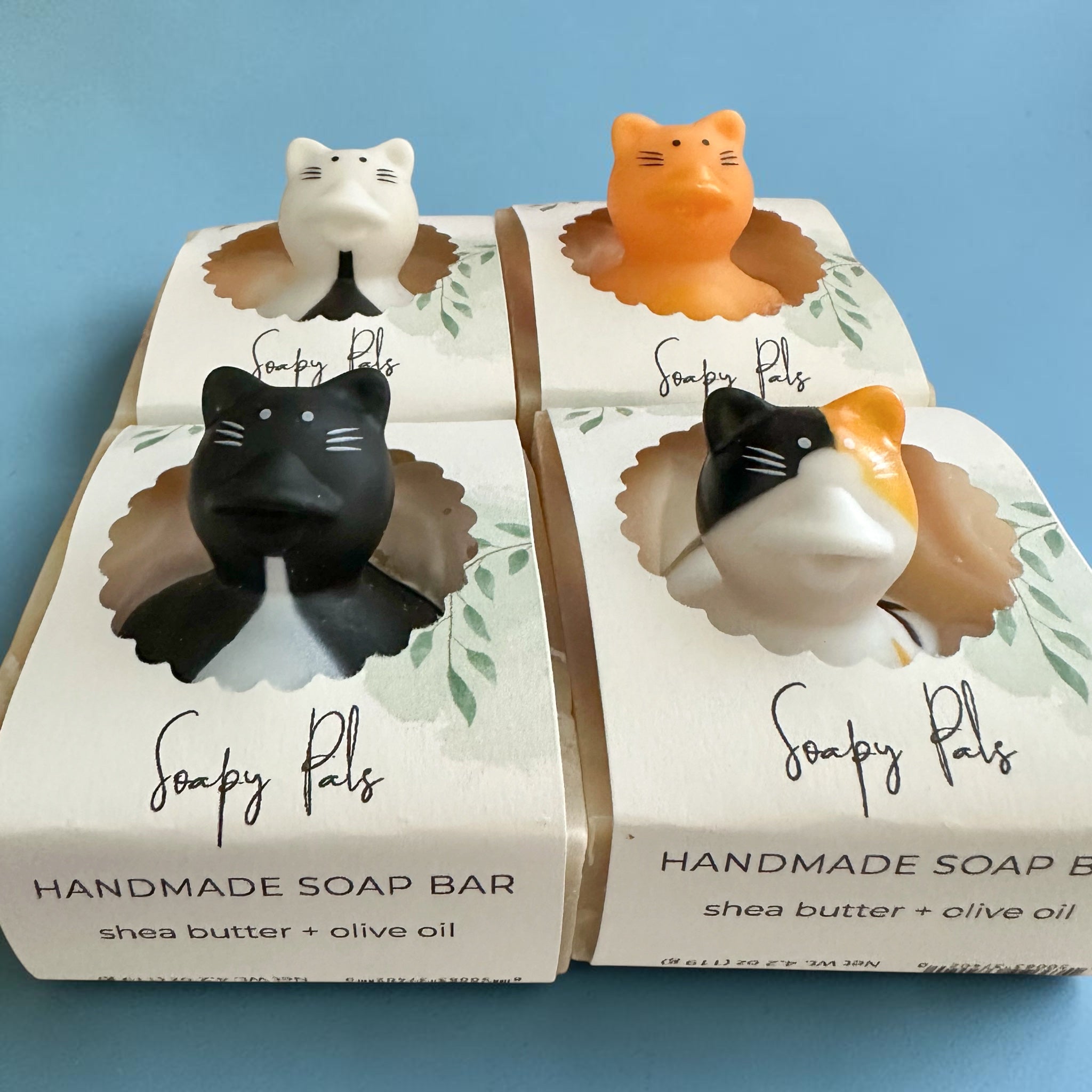 Set of two cat-themed handmade soap bars, orange and white with black markings.