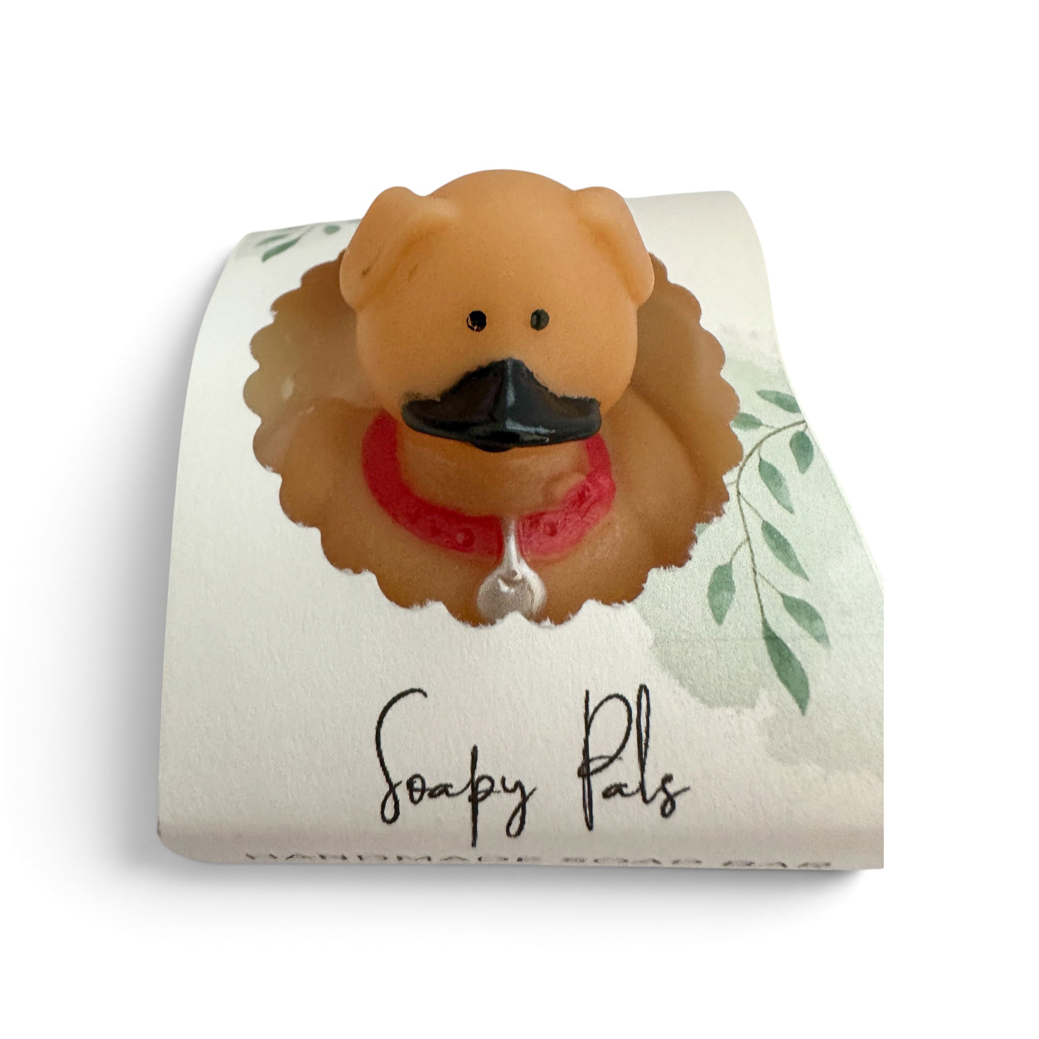 Handmade soap bar shaped like an orange dog wearing a red bandana and holding a nose.
