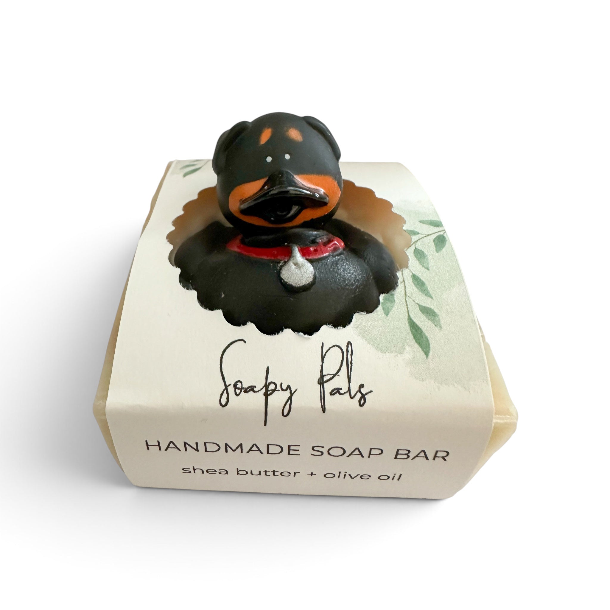 Handmade soap bar shaped like a black dog with orange paws and a red bandana.