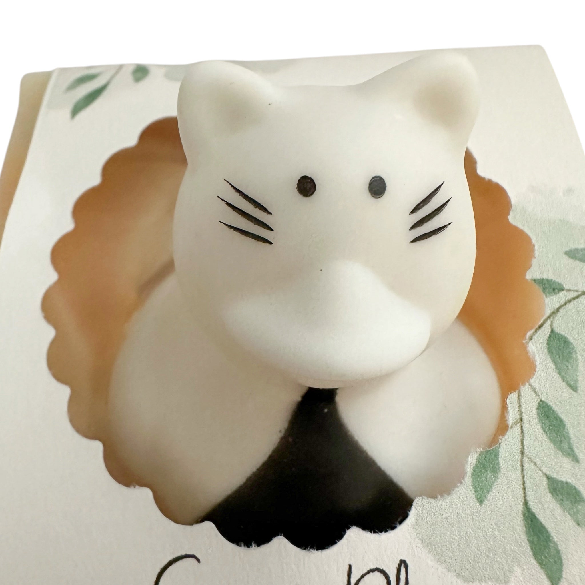 Handmade soap bar shaped like a white cat with dark ears, nose, and whisker lines.