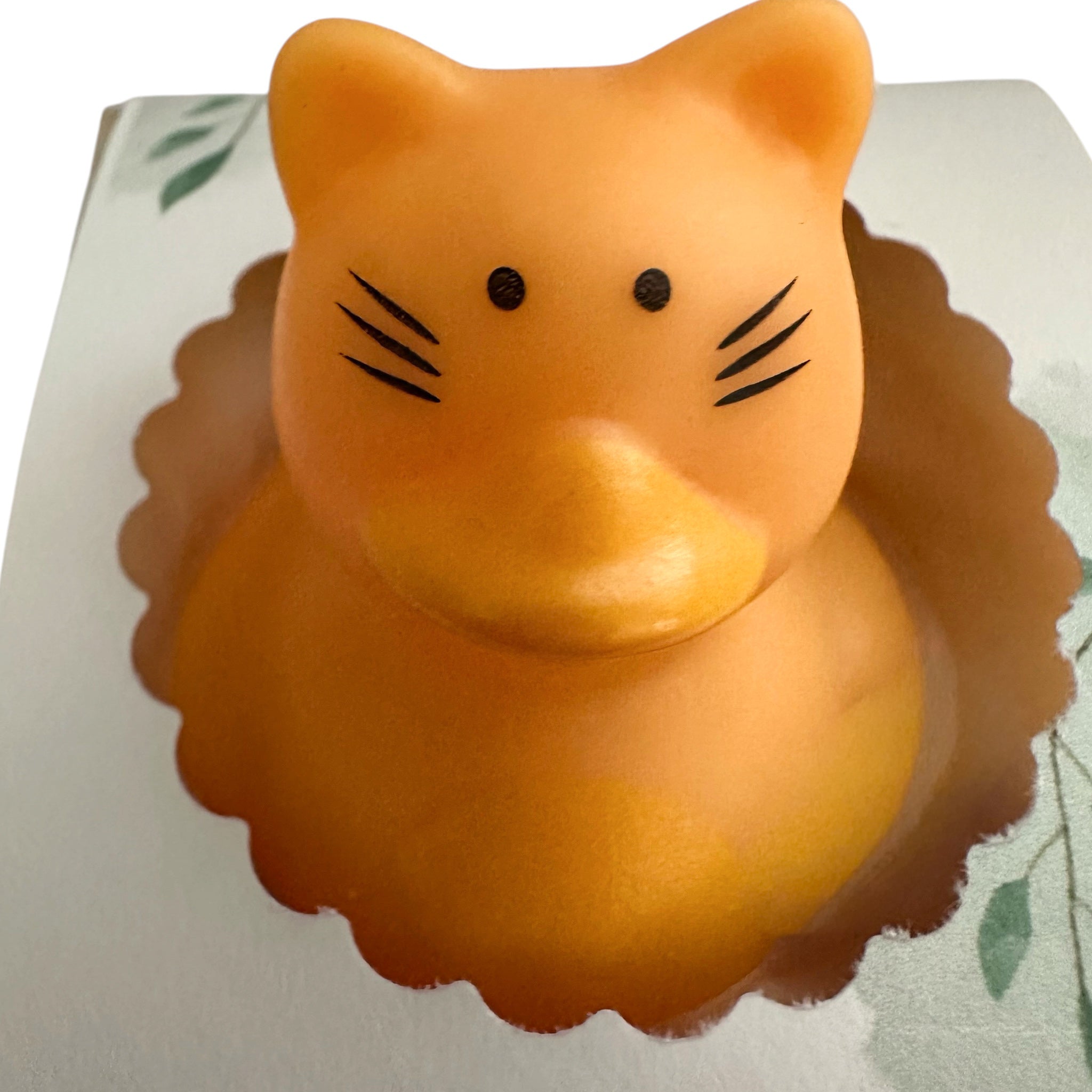 Handmade soap bar shaped like an orange cat with simple eyes and whisker lines.