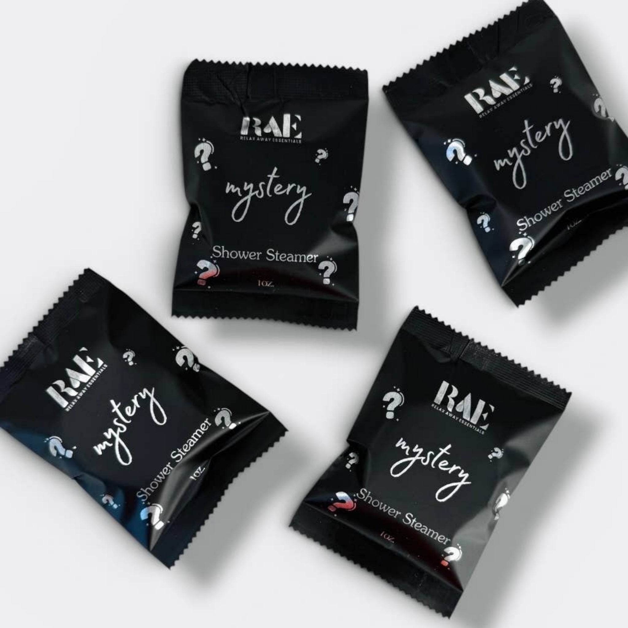 Set of RAE mystery shower steamer packets, black foil sachets with mystery text and icons