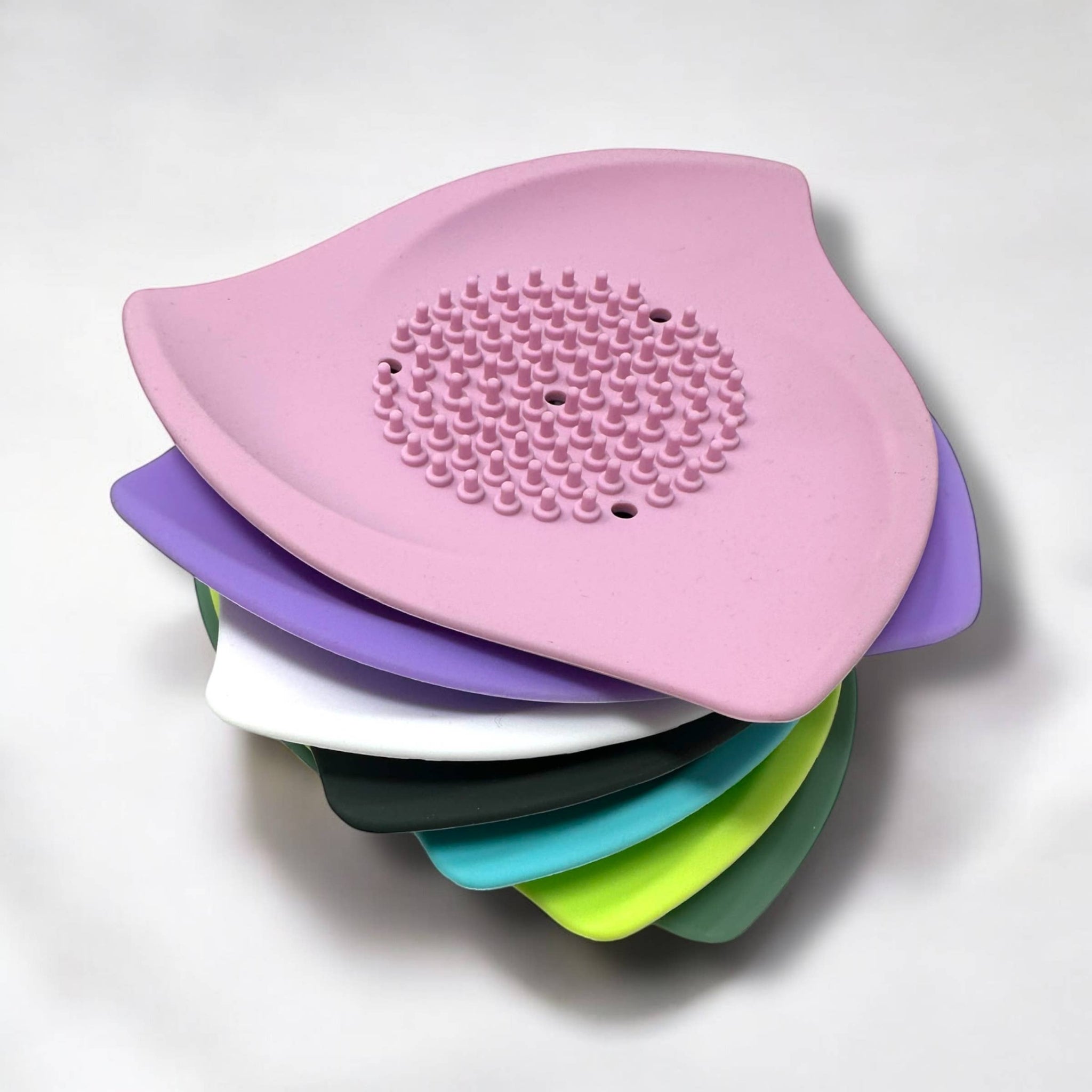 Pink silicone shower steamer tray stacked with purple, white, green, teal, and lime trays
