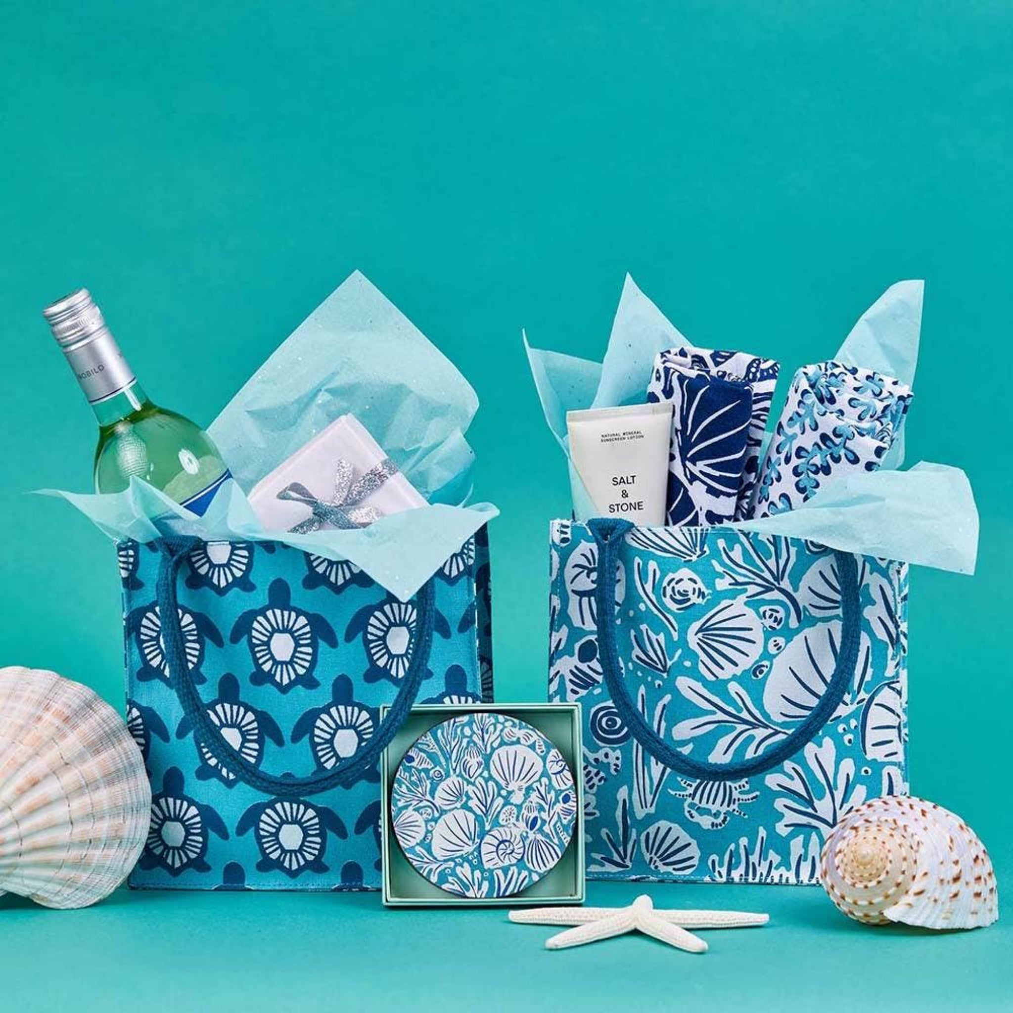 Two blue gift bags with sea-themed items on a teal background