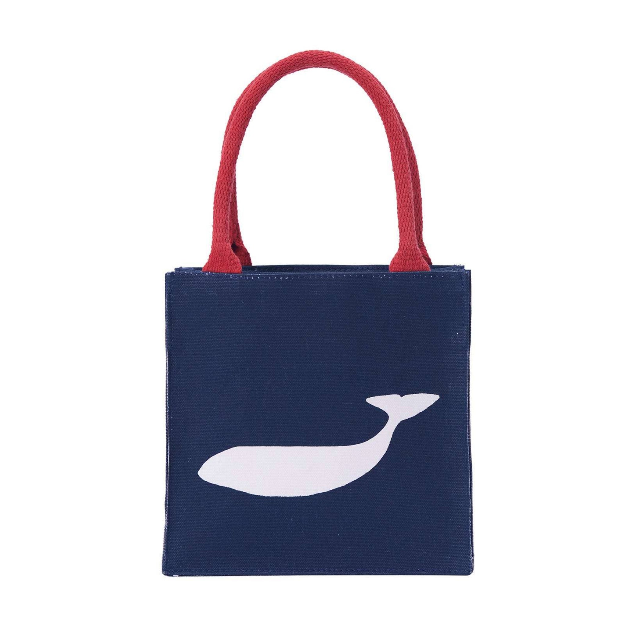 A navy blue canvas tote bag with red fabric handles and a white whale silhouette printed on the front, shown against a plain white background.