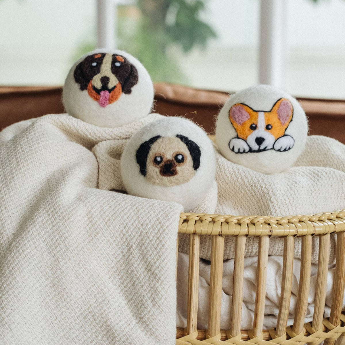 Three natural wool dryer balls featuring a dog, pug, and corgi face design