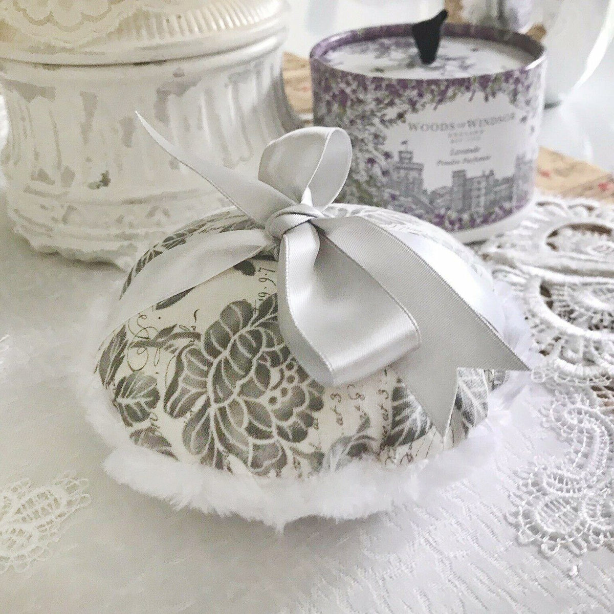 Large gray-and-white floral powder puff with satin bow and fluffy white trim
